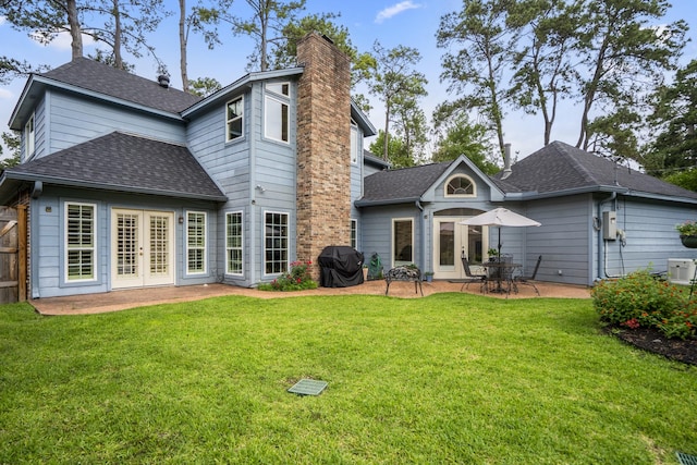 rear view of house with a yard, a patio area, roof with shingles, and french doors