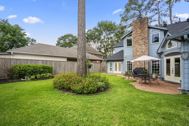 rear view of property featuring fence, a patio, french doors, a chimney, and a lawn