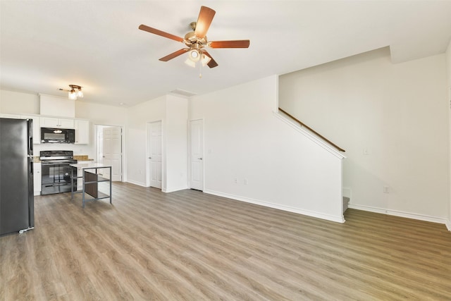 unfurnished living room with a ceiling fan, baseboards, and light wood-style flooring