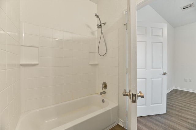 full bathroom with vaulted ceiling, visible vents, baseboards, wood finished floors, and tub / shower combination