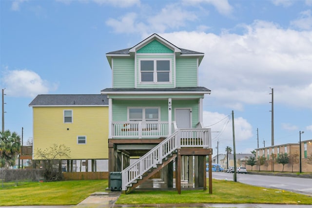 beach home featuring a porch, a front yard, and stairway