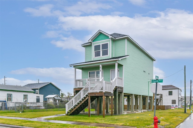 view of front facade featuring fence, a front lawn, covered porch, and stairs