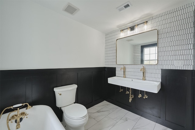 1323 Ball, Galveston, TX 77550 - bathroom with marble look tiles, a sink, toilet, a freestanding tub, and a wainscoted wall