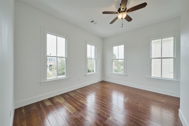 spare room featuring dark wood-style floors, baseboards, ceiling fan, and visible vents