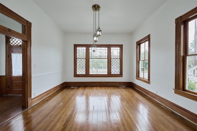 unfurnished dining area with wood-type flooring, baseboards, and ornamental molding
