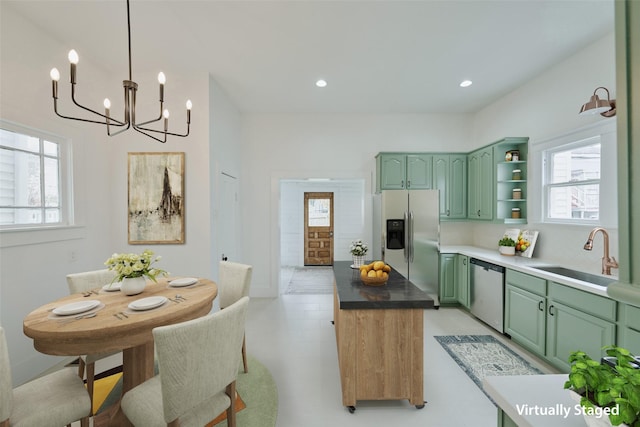 kitchen with plenty of natural light, green cabinetry, an inviting chandelier, a sink, and appliances with stainless steel finishes