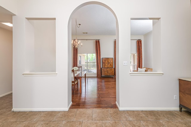 6249 Mallard Dr, Katy, TX 77493 - hallway with arched walkways, an inviting chandelier, tile patterned flooring, and baseboards
