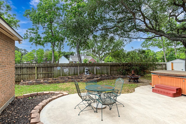 6249 Mallard Dr, Katy, TX 77493 - view of patio featuring a storage unit, a fenced backyard, a hot tub, an outdoor structure, and an outdoor fire pit
