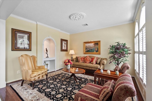 living area with baseboards, visible vents, wood finished floors, and ornamental molding
