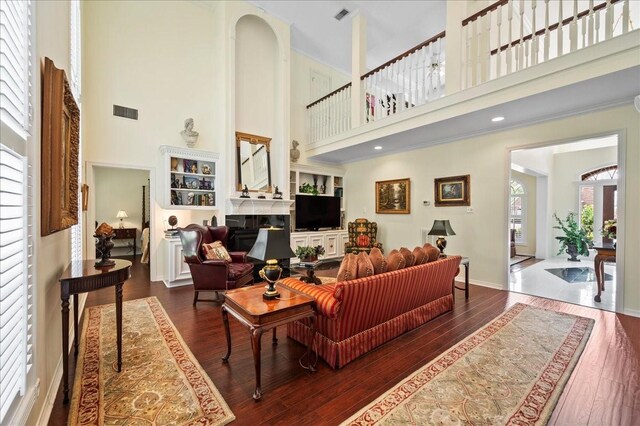 living area with visible vents, a fireplace, and a towering ceiling