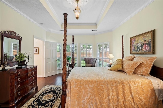 bedroom with baseboards, dark wood-style floors, visible vents, crown molding, and a tray ceiling
