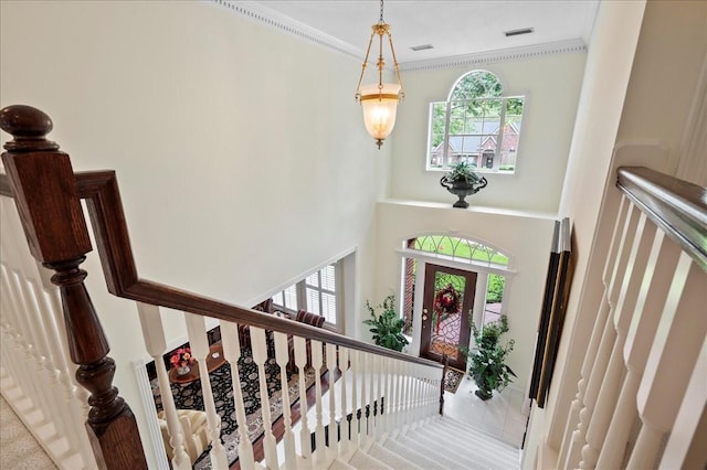 foyer with stairway, visible vents, crown molding, and a high ceiling