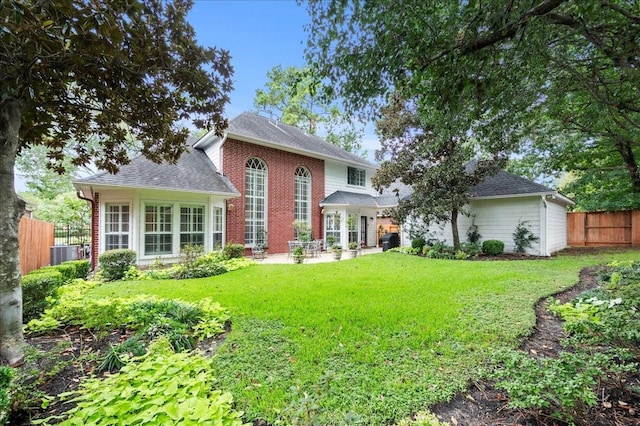 back of property with a patio area, a shingled roof, fence, a yard, and central AC
