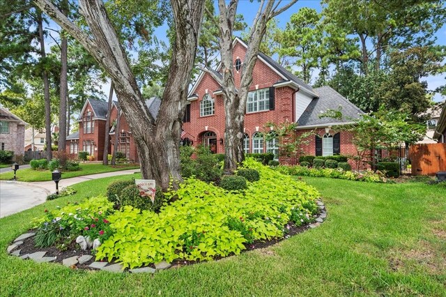 view of front of house with brick siding, fence, a front yard, and roof with shingles