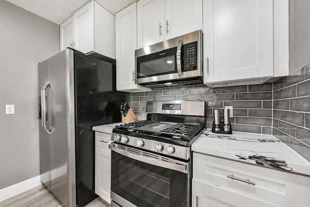3626 Lake Breeze Ln, Crosby, TX 77532 - kitchen featuring white cabinets, stainless steel appliances, baseboards, and decorative backsplash