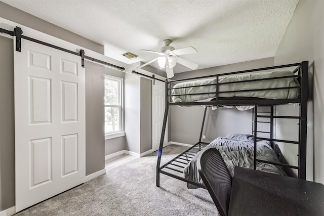 3626 Lake Breeze Ln, Crosby, TX 77532 - carpeted bedroom with a textured ceiling, a barn door, baseboards, visible vents, and ceiling fan