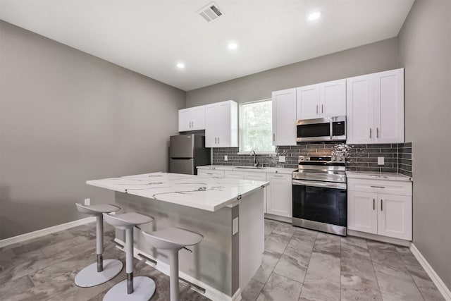 3626 Lake Breeze Ln, Crosby, TX 77532 - kitchen with stainless steel appliances, visible vents, a sink, a center island, and a kitchen bar