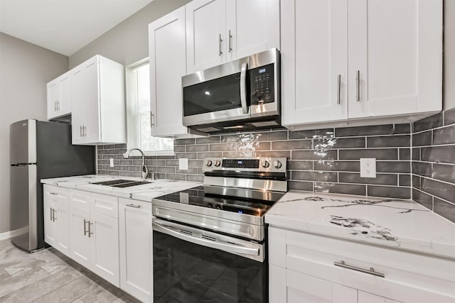 3626 Lake Breeze Ln, Crosby, TX 77532 - kitchen with light stone countertops, white cabinetry, stainless steel appliances, and a sink