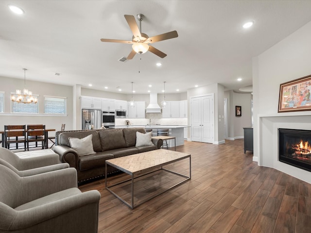 7262 Monarch Dr, Katy, TX 77493 - living room featuring recessed lighting, a glass covered fireplace, dark wood finished floors, and ceiling fan with notable chandelier