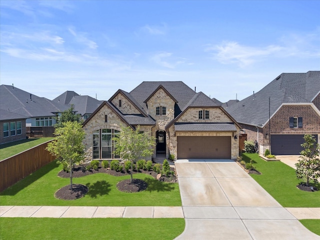 7262 Monarch Dr, Katy, TX 77493 - french country style house featuring driveway, fence, a front lawn, an attached garage, and stone siding