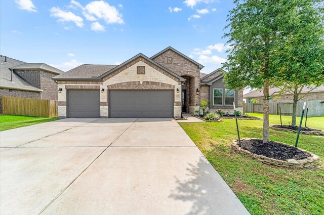 french provincial home with concrete driveway, a front lawn, stone siding, fence, and a garage