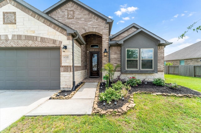 view of front of home with fence, a front lawn, driveway, stone siding, and brick siding