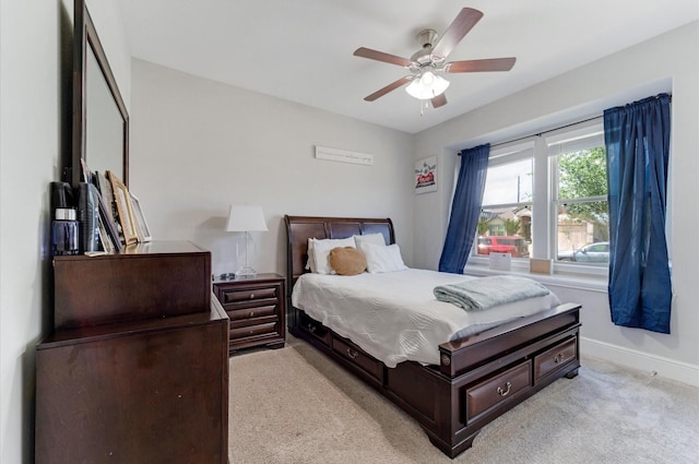 bedroom featuring light colored carpet, baseboards, and a ceiling fan