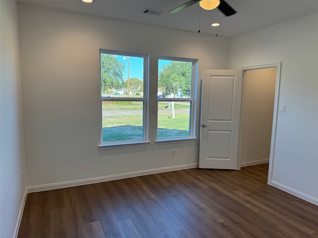 spare room with visible vents, a ceiling fan, baseboards, and dark wood finished floors