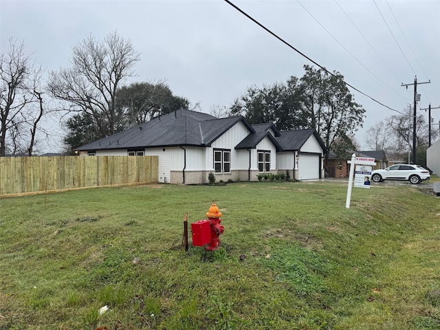 exterior space with a front lawn, fence, board and batten siding, and a garage