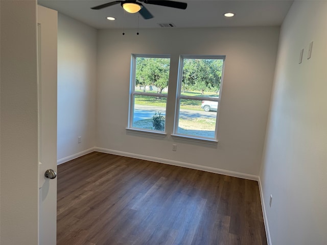 unfurnished room with baseboards, a ceiling fan, visible vents, and dark wood finished floors
