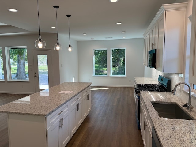 kitchen featuring plenty of natural light, dark wood-style flooring, stainless steel gas stove, and a sink