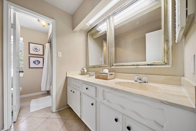 full bathroom featuring tile patterned floors, baseboards, a sink, and double vanity