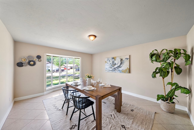 dining space featuring baseboards, a textured ceiling, and light tile patterned floors