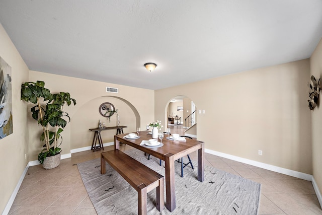 dining area with arched walkways, visible vents, baseboards, and light tile patterned flooring