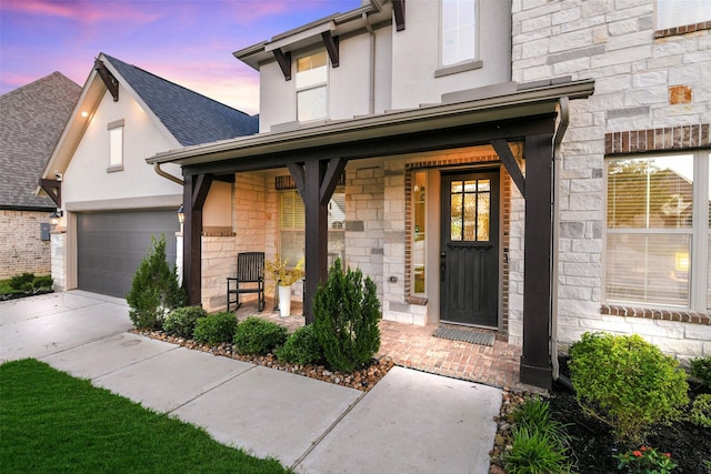 19219 Filly Park Cir, Tomball, TX 77377 - property entrance with stone siding, a porch, a garage, concrete driveway, and stucco siding
