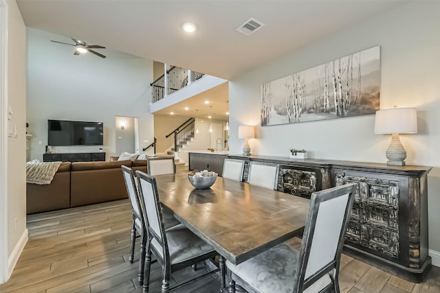 19219 Filly Park Cir, Tomball, TX 77377 - dining area featuring stairs, wood finished floors, ceiling fan, baseboards, and a towering ceiling