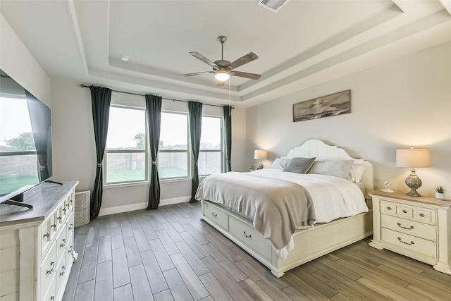 19219 Filly Park Cir, Tomball, TX 77377 - bedroom featuring a tray ceiling, wood finished floors, baseboards, and ceiling fan
