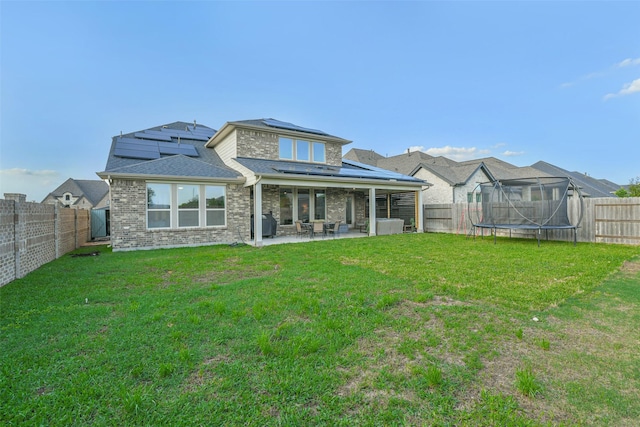 19219 Filly Park Cir, Tomball, TX 77377 - back of house featuring a trampoline, a patio, solar panels, brick siding, and roof with shingles