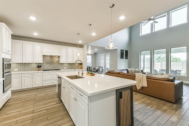 19219 Filly Park Cir, Tomball, TX 77377 - kitchen featuring a sink, open floor plan, light wood-style floors, a ceiling fan, and light countertops