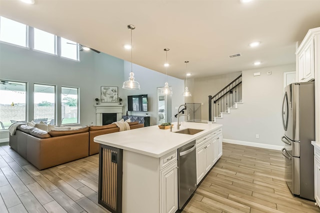 19219 Filly Park Cir, Tomball, TX 77377 - kitchen with stainless steel appliances, a sink, light wood-style floors, white cabinetry, and recessed lighting