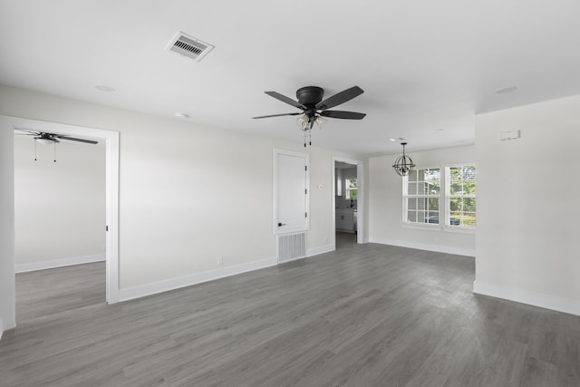 unfurnished living room with baseboards, wood finished floors, visible vents, and ceiling fan with notable chandelier