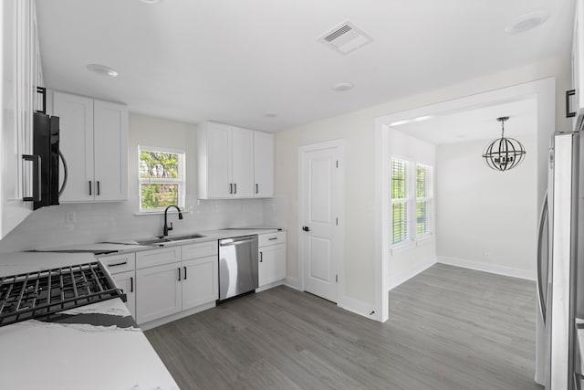 kitchen featuring a sink, light wood-style floors, a healthy amount of sunlight, stainless steel appliances, and visible vents