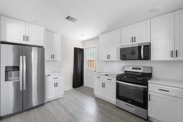 kitchen with light countertops, visible vents, decorative backsplash, light wood-style flooring, and appliances with stainless steel finishes