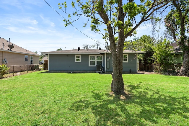 rear view of house featuring a lawn and fence