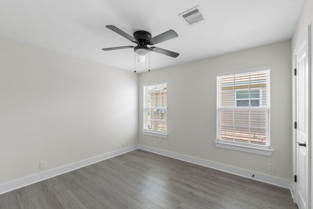 empty room featuring baseboards, visible vents, dark wood-type flooring, and ceiling fan