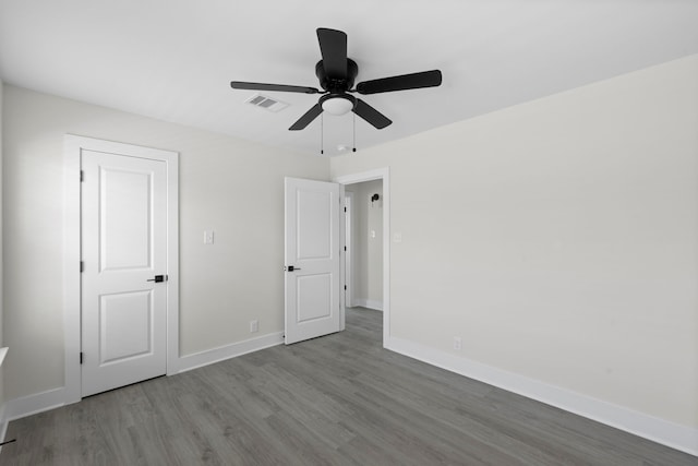 unfurnished bedroom with baseboards, a ceiling fan, wood finished floors, and visible vents
