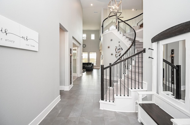 tiled foyer entrance with stairway, a high ceiling, baseboards, and an inviting chandelier