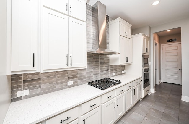 kitchen featuring wall chimney exhaust hood, recessed lighting, backsplash, white cabinetry, and appliances with stainless steel finishes