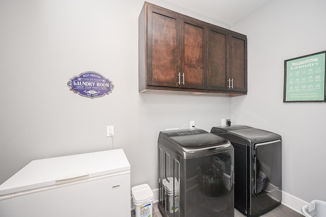laundry area with baseboards, washer and clothes dryer, and cabinet space