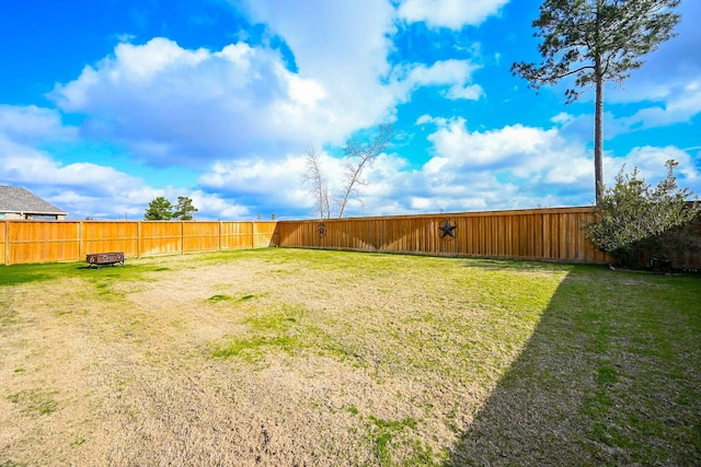 view of yard featuring a fenced backyard and a fire pit